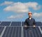 Male technician in a uniform posing behind solar cells