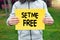 Male teenage boy holds a yellow banner with set me free text against nature background