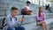 Male teenager chatting smartphone sitting beside classmate, online communication