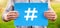 Male teenager holds a blue banner with hashtag symbol against nature background