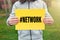 Male teenager holds a yellow banner with hashtag network message against nature background