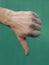 Male thumb down on green background