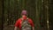 Male tourist with a backpack and a cap is walking along a forest path, rear view, camera movement