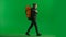 A male tourist with a backpack on his back walks in the studio on a green screen. Hiking trek rest travel trip concept