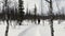 A male tourist with a backpack, ski poles and a smartphone in his hand walks along a snowy path in a winter forest. A male tourist