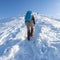 Male tourist with blue backpack rises in the snowy mountains. Ukrainian Carpathians in the winter.