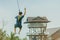 A male tourist flying on a zipline aka flying fox across the lake