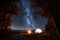 Male tourist have a rest in his camp near the forest at night under beautiful night sky full of stars and milky way