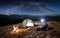 Male tourist have a rest in his camp at night under beautiful sky full of stars and milky way