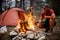 Male tourist kindles bonfire in front of a tent