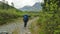 A male tourist with a large backpack walks along a path in the forest