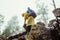 Male tourist in a raincoat during the raindescends from the cliff. Hiker on mountain rocks in rainy weather, dangerous descent