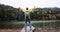 Male tourist stands on large stone against backdrop of forest and lake