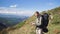 Male tourist stands on the mountain, takes out a paper map, looking for a way