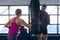 Male trainer giving boxing training to female athletic in fitness center