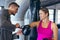 Male trainer helping female athletic to wear boxing gloves in fitness center