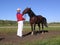 Male trainer holding a sports horse in the bridle engaged in a demonstration of the exterior