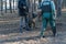 Male trainer in special protective clothing walks in front of the dog and its owner. Dog breed Cane Corso Italiano sits next to