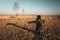 Male traveler with a backpack kneeling on the meadow, shadow shape of a cross, Nowiny, Poland