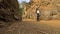 A male traveler with a backpack walks past large brown rocks in the mountains of Poland