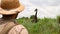 male traveler in safari style photographs a giraffe in the savannah