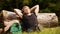 A male traveler sits beside the fallen tree trunk and fidgets with his feet