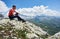 Male traveler sitting on top of rocky mountain.