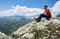 Male traveler sitting on top of rocky mountain.