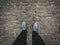 Male traveller legs in grey lifestyle sneakers shoes on vintage paving stones in old city for adventure and walking, top view