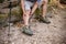 A male trekker sits on a wooden log and massages his leg, suffering from knee pain, leg cramping