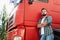 Male truck driver standing beside his red cargo truck