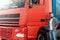 Male truck driver standing beside his red cargo truck