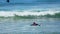 Male trying to swim on surfing board through waves in ocean, summer active sport