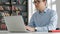 Male university student looking at laptop screen thoughtfully while doing homework. Closeup of concentrated boy trying