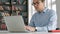 Male university student looking at laptop screen thoughtfully while doing homework. Closeup of concentrated boy trying