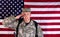 Male veteran solider saluting with USA flag in background while