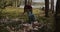 A male volunteer collects trash scattered in the forest in a plastic bag.