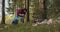 A male volunteer collects trash scattered in the forest in a plastic bag.