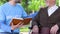 Male volunteer reading book to lonely disabled pensioner in park, social support