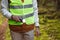 Male Volunteer of the Search and Rescue Team Dressed in a Signal Vest with a Flashlight in the Forest.