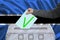 Male voter drops a ballot in a transparent ballot box against the background of the national flag of Botswana, concept of state