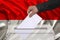 Male voter drops a ballot in a transparent ballot box against the background of the national flag of Monaco, Nuremberg, Indonesia