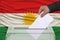 Male voter lowers the ballot in a transparent ballot box against the background of the national flag of Kurdistan, rojava, concept