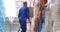 Male warehouse worker using ladder to arrange cardboard box