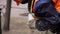 Male wearing orange uniform and helmet screws metallic sprayer tip to bottle.