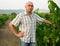 Male winemaker standing near grapes in vineyard at fields