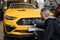 Male worker in gloves washes car radiator grille of luxury yellow car with special brush and soap