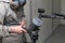 A male worker in jumpsuit and mask paints with a spray gun a part of the car interior element in black after being damaged. Auto