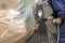 A male worker paints with a spray gun a part of the car body in silver after being damaged at an accident. Rear fender from the