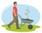 Male worker pushes a cart with a seedling for planting in the garden